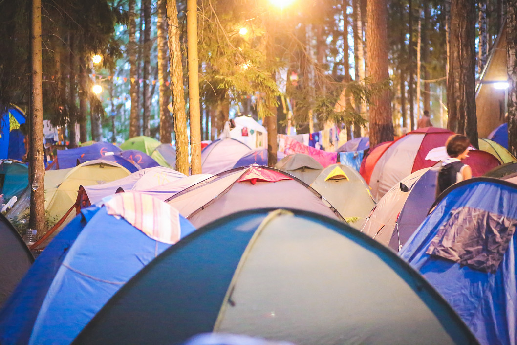 A group of campers at a music event with pitched tents